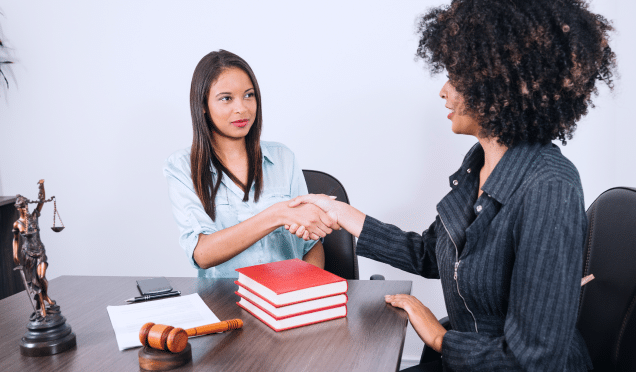 black-women-shaking-hands-table-with-books-smartphone-statue-document 1