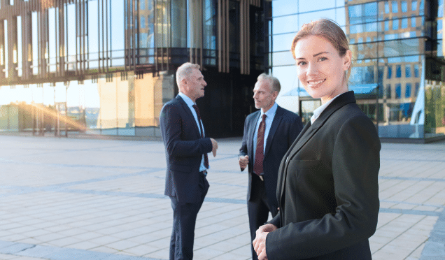 smiling-beautiful-business-woman-wearing-office-suit-standing-outdoors-looking-camera-talking-businesspeople-city-buildings-background-copy-space-female-portrait-concept 1